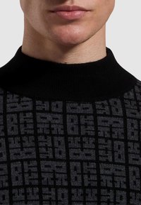 Maglione a maglia nera con colletto alto e un intricato motivo geometrico grigio su tutta la superficie, che conferisce un aspetto testurizzato.
