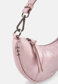 Sac en cuir rose à finition métallique, forme incurvée et garnitures argentées. Dispose d'une fermeture éclair et d'une couture décorative.