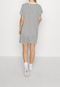 Raidallinen t-paitamekko valkoisena ja mustana, lyhyet hihat, rento istuvuus, pyöreä helma, yhdistetty valkoisiin tennareihin ja sukkiin.