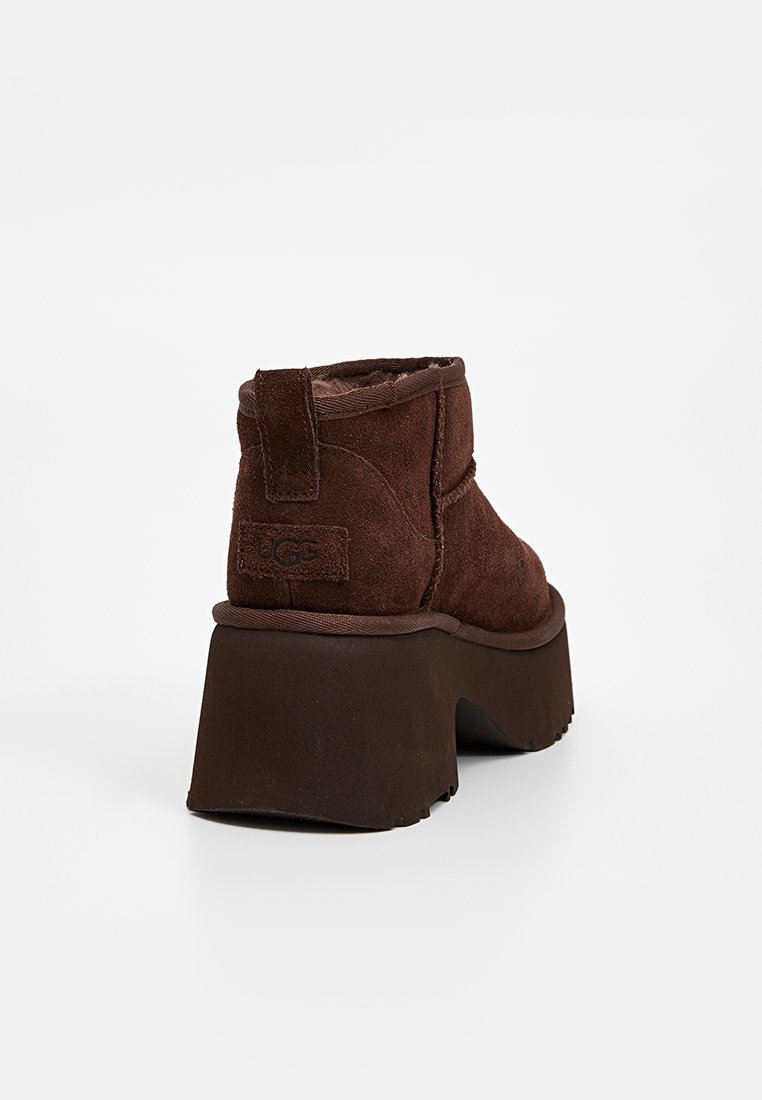 Bottines en daim marron avec un bout rond, une semelle à plateforme surélevée et une languette à l'arrière. Présentent des détails texturés et un intérieur doux.