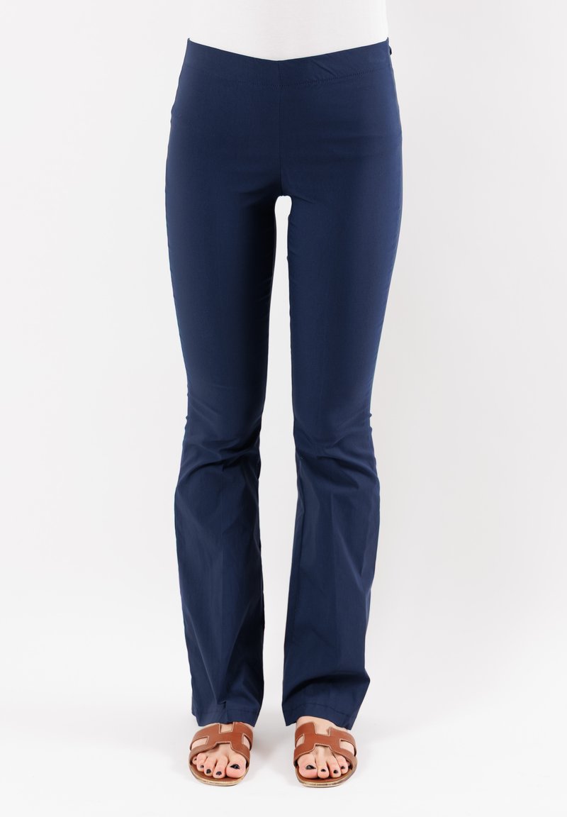 Pantaloni attillati di colore blu navy, realizzati in tessuto elastico con fondo svasato. Presentano una vita elasticizzata. Indossati con sandali marroni con cinturini.