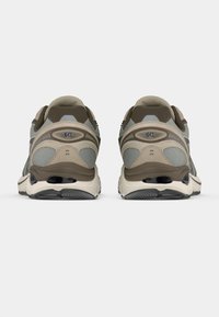 Αθλητικά παπούτσια με γκρι πλέγμα πάνω μέρος, μπεζ λεπτομέρειες και μαύρη καουτσούκ σόλα. Έχουν επενδεδυμένο κολάρο αστραγάλου και υφή στις λεπτομέρειες.