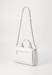 Quiltowana biała torebka z podwójnymi uchwytami, łańcuszkowym paskiem na ramię, kieszenią na zamek i gładką teksturą.