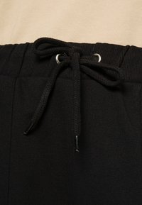 NA-KD PAMELA REIF x NA-KD - TRACKSUIT BOTTOMS - Calças de fato de treino - black