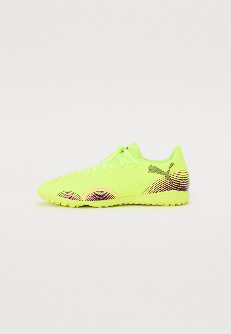 Scarpe da ginnastica verde-gialle con una tomaia texture, schemi circolari in rosa e viola, e una suola in gomma. Presentano un design con lacci e un marchio.
