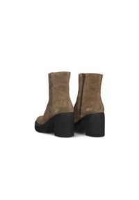 Bottines en daim marron avec un large talon noir et détail de fermeture éclair sur le côté. Le design est lisse avec une finition texturée.