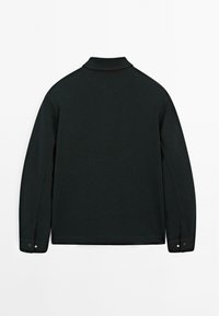Polo à manches longues noir en tissu texturé, avec un col décontracté et des poignets à boutons pour une fermeture sécurisée.