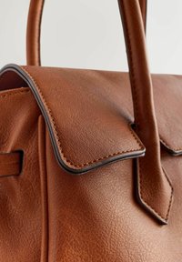 Hnědá kožená kabelka s pevnou strukturou, zavíráním na klopu, tmavě hnědým lemováním a viditelnými šicími detaily. Rukojeti jsou hladké a zaoblené.