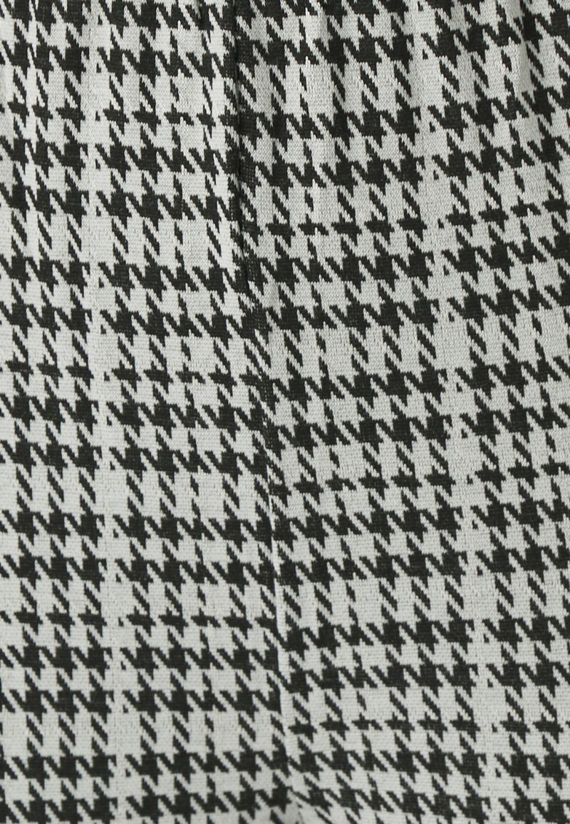 Svartvit houndstooth-mönstrad tyg med en texturerad väv, skarpa vinklar och kontrasterande färger.