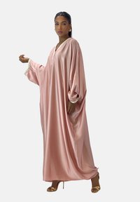 Lang, flydende pink satin kjole med brede ærmer og V-hals. Har pyntedetaljer langs udskæringen og manchetterne. Bæres med guld sandaler.