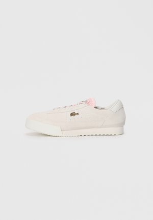 Zapatillas de ante beige con suela de goma blanca, cordones rosas y un logotipo sutil. Presenta puntera redondeada y acentos texturizados en los laterales.