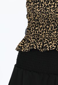 Top mit braunem und schwarzem Leopardenmuster, das aus gerafftem Stoff besteht, einen Rüschensaum hat und ein geschmücktes schwarzes Band in der Taille. Etikett mit der Aufschrift "SEASIDE."