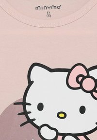 Helles rosa Baumwoll-T-Shirt mit schwarz umrandetem Cartoon-Katze-Motiv. Die Katze hat eine pinke Schleife, eine gelbe Nase und ein weißes Gesicht auf der Vorderseite.