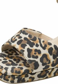 Sandale à imprimé animal beige avec une large bride, une texture douce semblable au daim et une semelle robuste. Le motif présente des taches de léopard noires et marron.