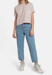 Pasiasty, pastelowy T-shirt w odcieniach różu, zieleni i niebieskiego; luźny krój. Połączony z jasnoniebieskimi, wysokimi dżinsami i wielokolorowymi trampkami.