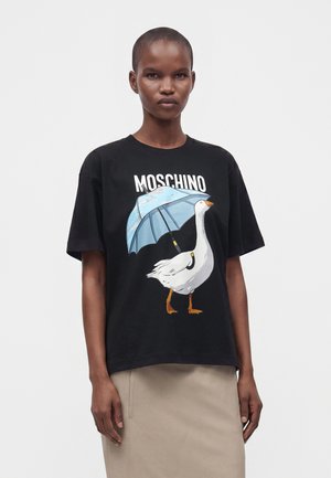Person iført en sort Moschino t-shirt med en hvid gås, der holder en blå paraply, og en beige nederdel.