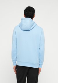 Ανοιχτό μπλε φούτερ με άνετη κουκούλα, μακριά μανίκια �και ραμμένα μανσέτα. Διαθέτει μαλακό, υφασματώδη ιστό και χαλαρή εφαρμογή.