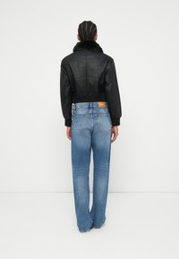 Czarna krótka kurtka z futrzanym kołnierzem, zestawiona z jasnoniebieskimi szerokimi spodniami. Gładka skórzana tekstura i kontrastowe detale szwów.