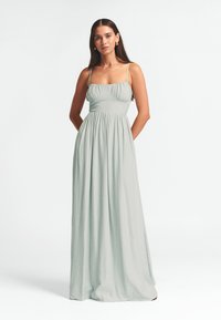 Hellgrünes Maxikleid mit dünnen Trägern, gerafftem Oberteil und fließendem Rock. Hergestellt aus strukturiertem Stoff mit lockerem Schnitt.