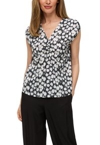 Zwart-witte blouse met patroon, voorzien van een V-hals en kapmouwen, met een geraffineerde detail in het midden voor extra textuur.
