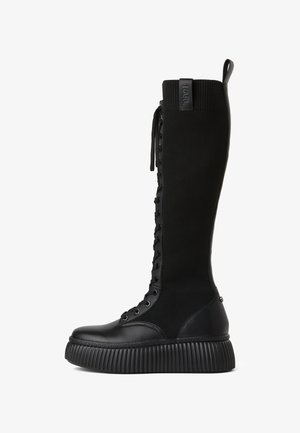 Zwarte kniehooglaarzen met een ribbeltextiel bovenwerk, vetersluiting aan de voorkant en een ronde rubberen plateauzool met verticale groeven.
