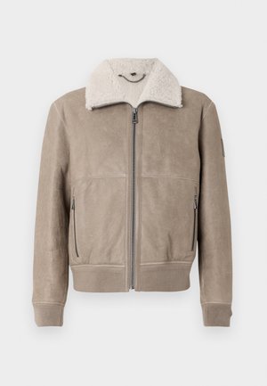 Tan suede jacket with a textured finish, featuring a cream shearling collar, zippered front, and two side pockets. Ribbed cuffs.