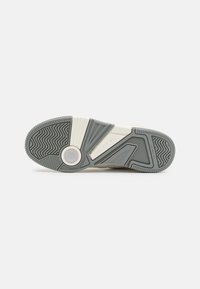 Semelle extérieure de chaussure en caoutchouc gris avec motif de bande de roulement texturé. Présente un accent circulaire et le logo de la marque. Le matériau semble durable et flexible.