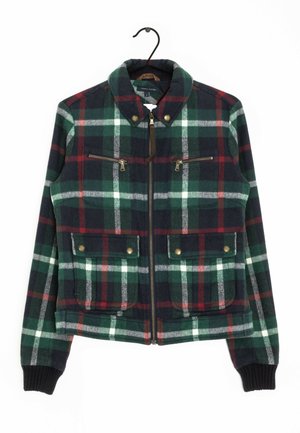 Grøn, marineblå, rød og hvid ternet jakke med lynlås, opretstående krave, to lynlåslommer på brystet, to klaplommer med trykknapper og ribstrikkede manchetter.