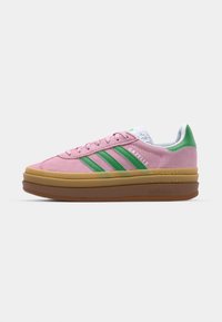 Pink suede sneakers with green accents, featuring three stripes, a thick yellow midsole, and a textured white tongue.