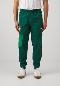 Gröna träningsbyxor gjorda av lätt material, med en sidoficka, elastisk midja med dragsko, och Portugals emblem på vänster lår.