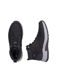 Zapatos negros de media caña con parte superior de cuero suave, diseño de cordones, cuello acolchado y suela de goma gris. Presenta el logo en el lateral y en la lengüeta.