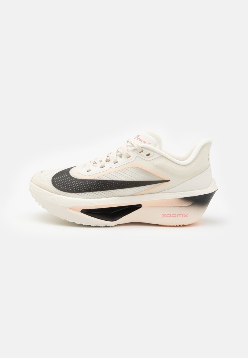 Sapatilha desportiva branca com uma entressola preta e rosa, parte superior texturizada e o distintivo swoosh da Nike, apresentando atacadores e um colarinho acolchoado.