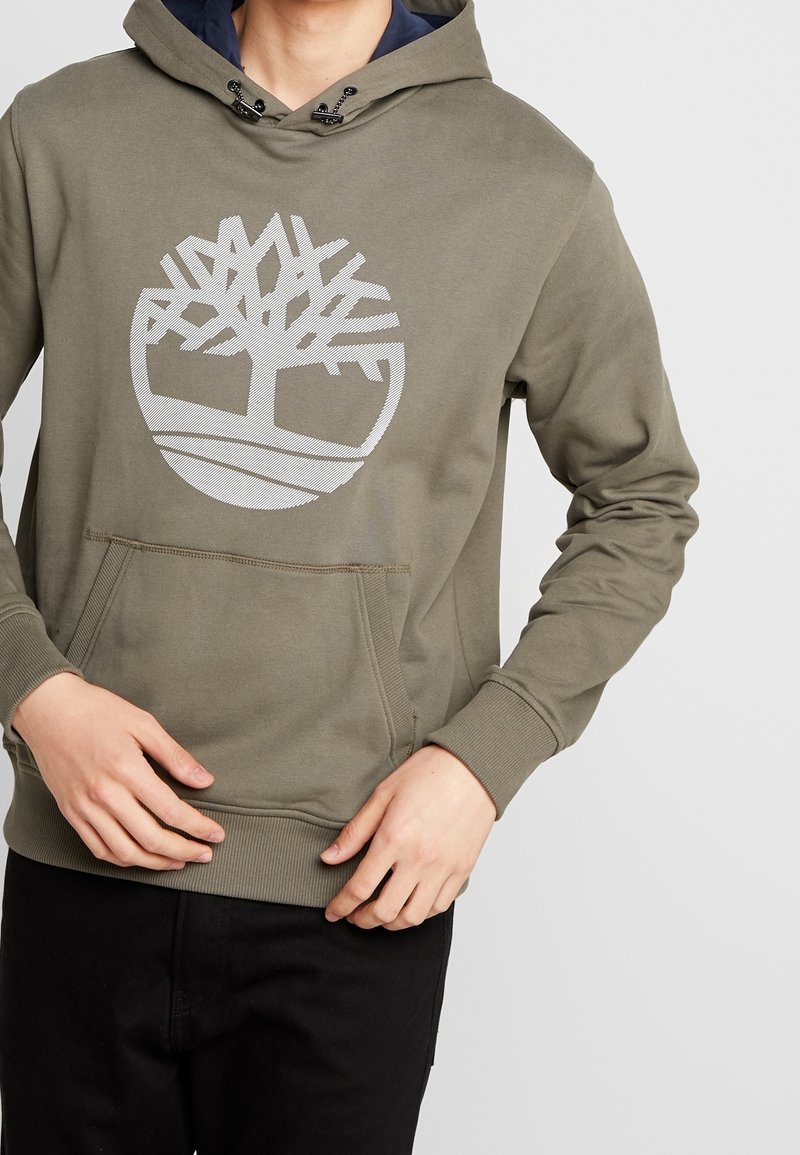 Olivegrüner Hoodie aus weichem Stoff mit großem weißen Baum-Logo, Kängurutasche und verstellbarem Kordelzug an der Kapuze.