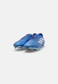 Scarpe da calcio blu con una superficie liscia e lucida, caratterizzate da strisce bianche, design con lacci e tacchetti traslucidi sulla suola.