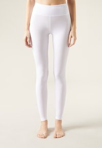 Leggings bianchi con un alto punto vita, realizzati in un materiale morbido e elastico. Hanno un design aderente e una finitura senza cuciture alla caviglia.