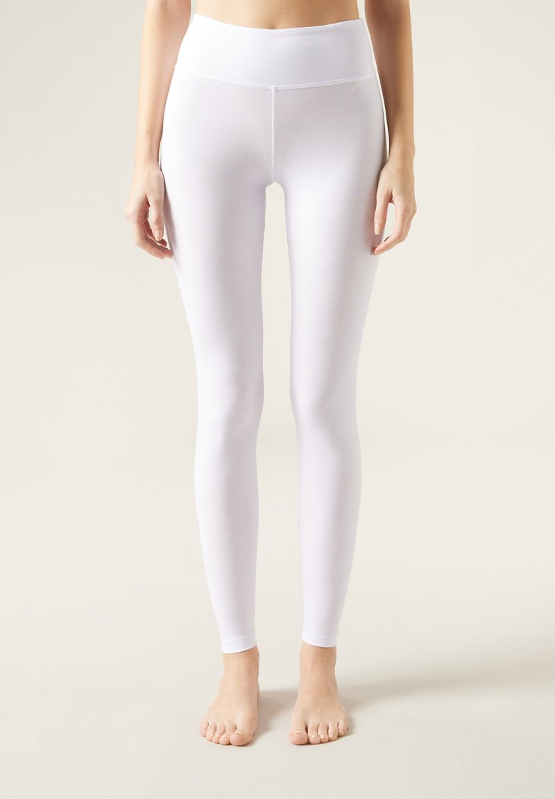 Leggings bianchi con un alto punto vita, realizzati in un materiale morbido e elastico. Hanno un design aderente e una finitura senza cuciture alla caviglia.