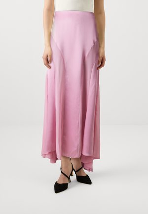 Pink satin maxi skirt with a high-low hem, featuring smooth texture and curved side panels, paired with black strappy heels.