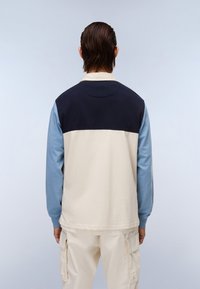 Dlouhý rukáv košile s barevným blokem v námořnické modři, světle modré a krémové. Vyrobena z měkké tkaniny s uvolněným střihem a žebrovaným výstřihem.