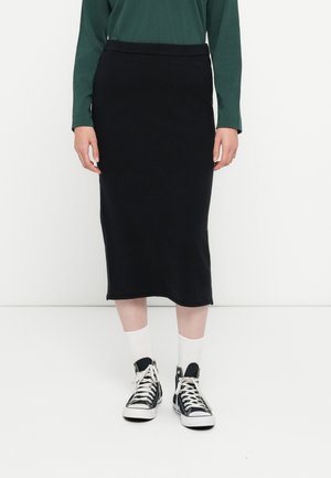 Jupe crayon en maille noire au design ajusté, longueur genou, avec une texture lisse et une taille élastique, associée à des baskets montantes.