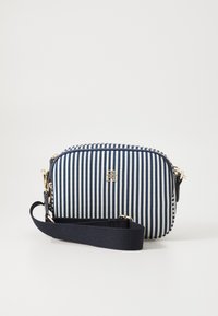 Niebieska i biała torebka crossbody w paski z złotymi akcentami, zamykana na zamek, wykonana z teksturowanej tkaniny. Regulowany pasek dla wygody.