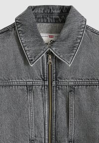 Γκρι τζιν μπουφάν με φερμουάρ, μυτερό γιακά και δύο τσέπες εμπρός. Διαθέτει αντίθετη ραφή και μαλακή, υφ ή φινιρίσματος.