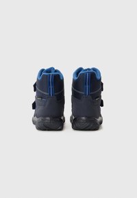 Pár tmavě modrých zimních bot s černými podrážkami, modrou podšívkou a dvěma suchými zipy, zobrazený zezadu na bílém pozadí.