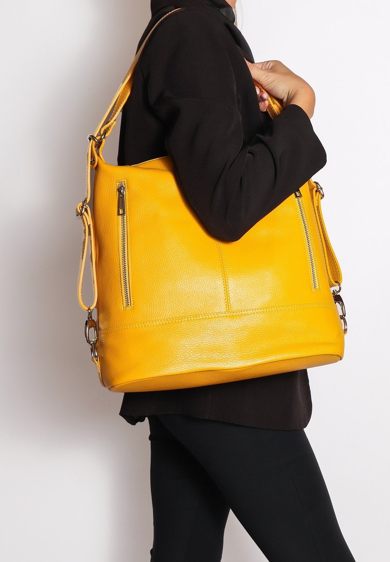 Borsa a mano gialla in pelle con finitura texturizzata, dotata di tasca con zip e tracolla, presentata su uno sfondo neutro.