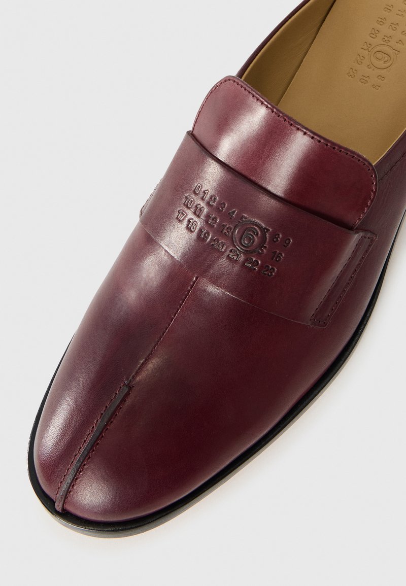 Burgundy leather shoe with a smooth texture, featuring a prominent band with embossed numbers and a rounded toe shape. Flat black sole.