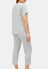 Grijze lounge-outfit gemaakt van zacht stof. T-shirt met korte mouwen en witte bies, en cropped broeken. Eenvoudige, ontspannen pasvorm zonder patronen.