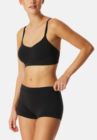 Svart mjuk bralette med justerbara remmar och ett brett band, i kombination med matchande svarta boyshorts med sömlöst design och mjuk textur.