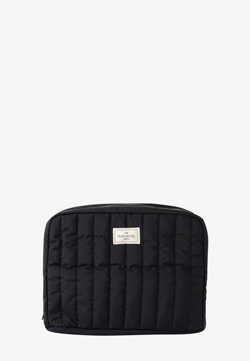 Czarna, pikowana, prostokątna saszetka na suwak z pionowym przeszyciem i małą białą metką marki umieszczoną centralnie u góry.