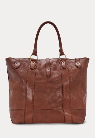 Sac fourre-tout en cuir marron avec doubles poignées, anneaux dorés, bandes verticales cousues et détail de fermeture par languette au centre.