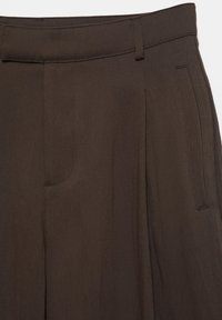 Dunkelbraune, maßgeschneiderte Hose mit Gürtelschlaufen und seitlichen Eingrifftaschen, vor einfarbigem Hintergrund präsentiert.