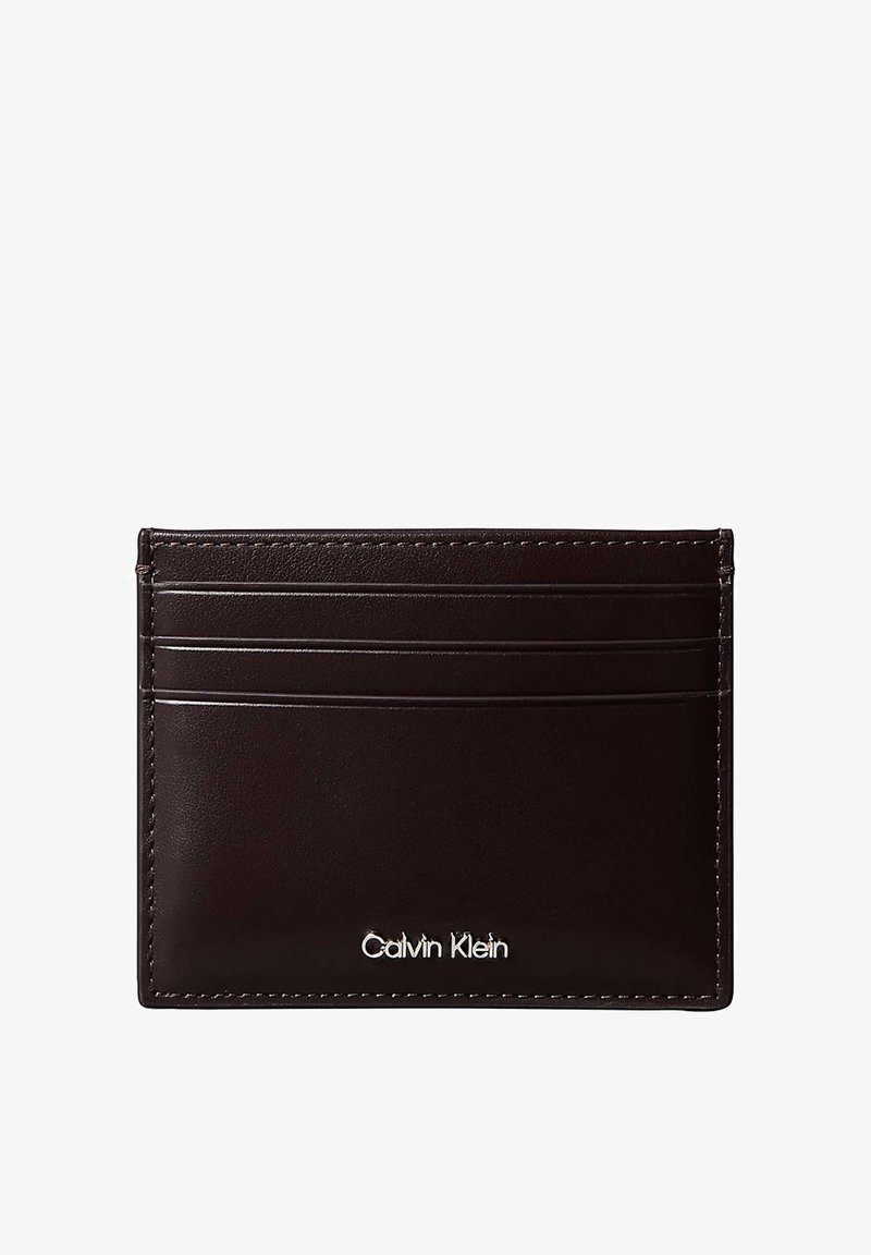 Porte-cartes en cuir marron foncé avec quatre emplacements pour cartes et logo Calvin Klein argenté dans le coin inférieur droit.